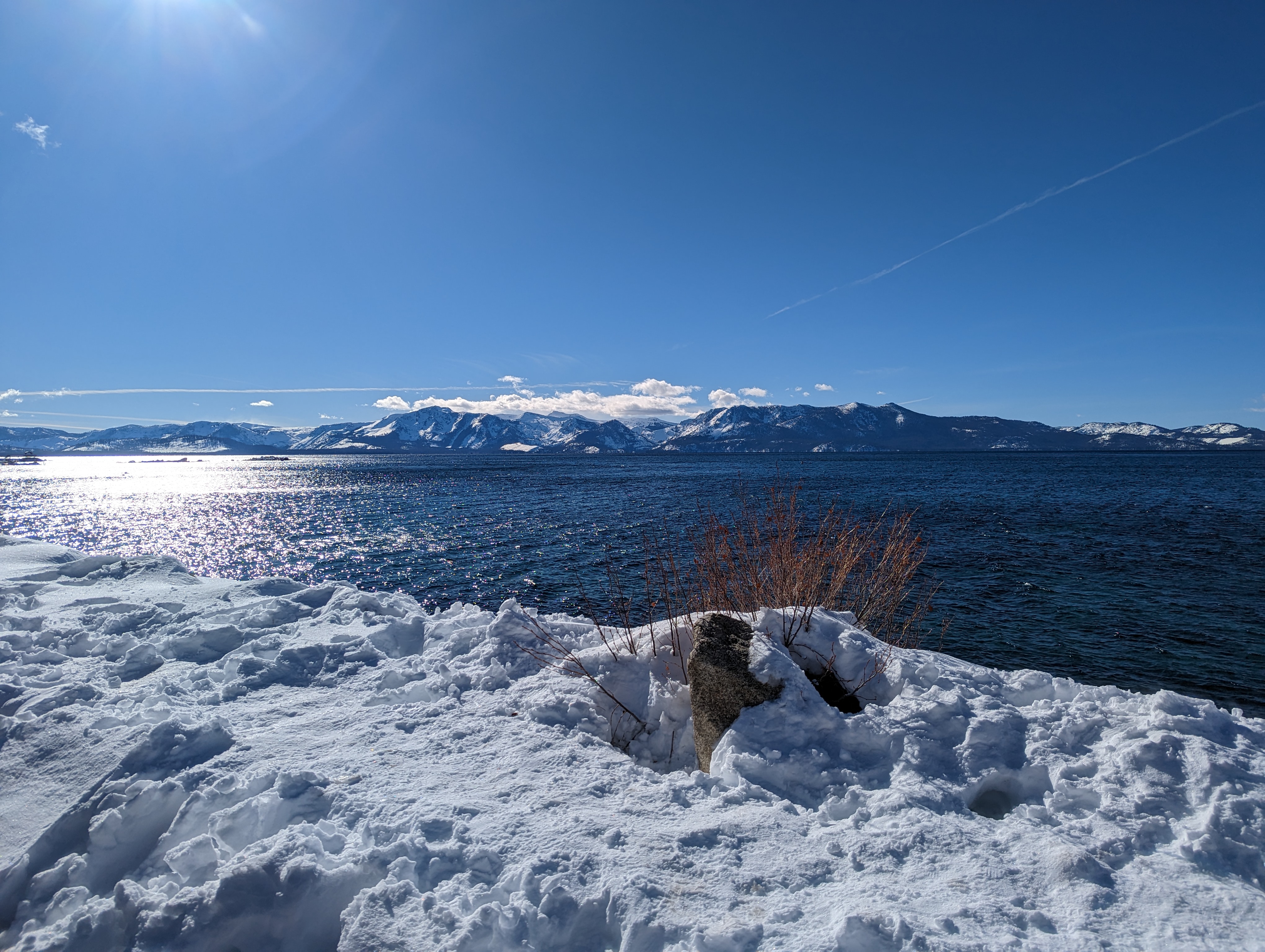 Photo Looking over lake Tahoe with deep snow on the Bank and snow caped mountains in the distance