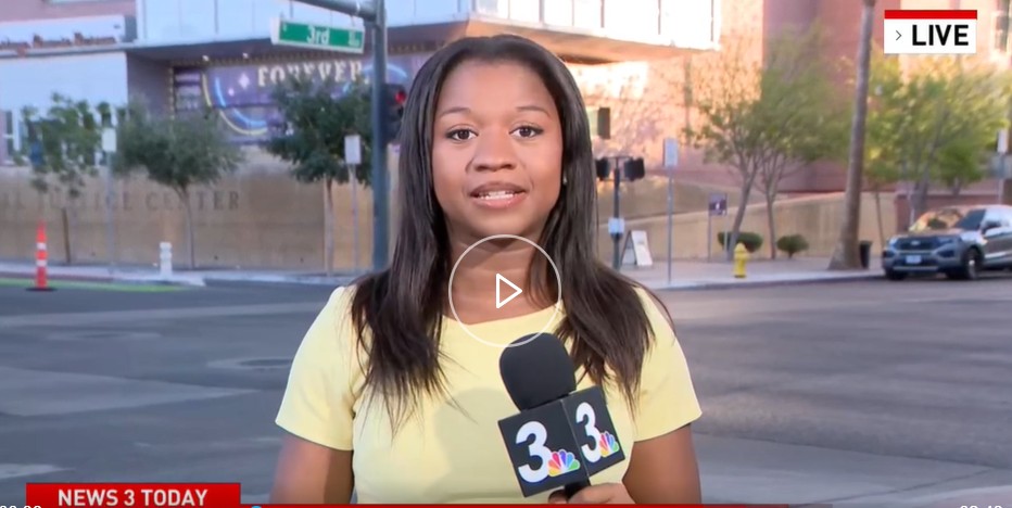 Woman wearing yellow shirt talking into reporter microphone standing at an intersection